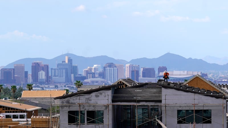 FILE - In this Aug. 12, 2021, file photo with the downtown skyline in the background, a roofer...